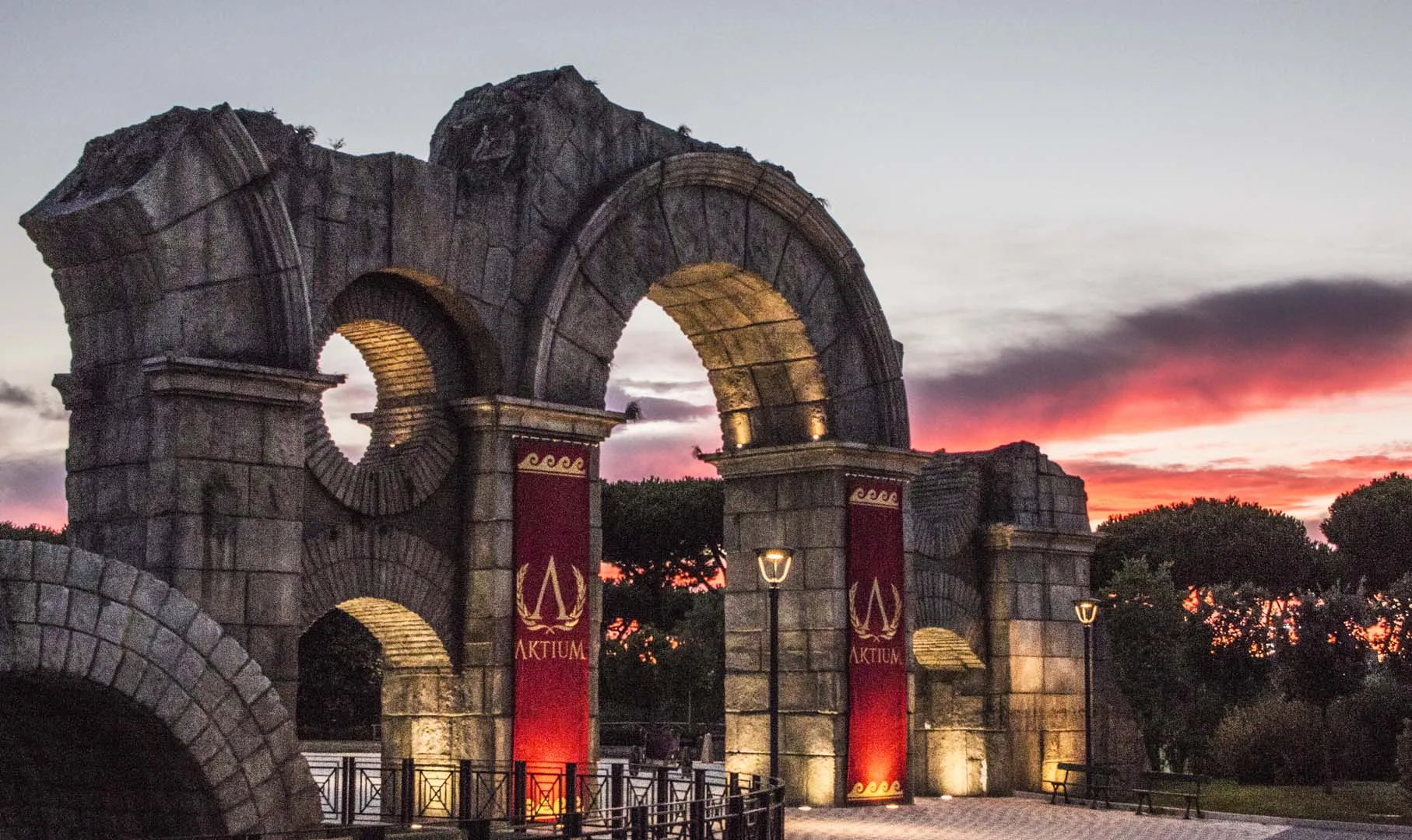 Roman triumphal arch 'Aktium' at sunset, red-violet sky, park's Roma area
