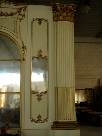 Detail of the Sissi Hall in Dubai: Corinthian column with flat base, fluted shaft with gilded reliefs, richly worked capital with gold acanthus leaves; to the left an arched French window with white-and-gold frame inlaid with rocaille; lower mirror panel with baroque frame