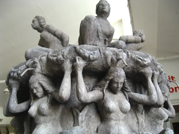 The life-size replica of the Fountain of the Four Moors sculpted in the Creation Art workshop: four female caryatid figures holding up a pedestal, three further full-round sculpted figures above in classical poses, weathered faux stone finish in antique grey, frontal view from below