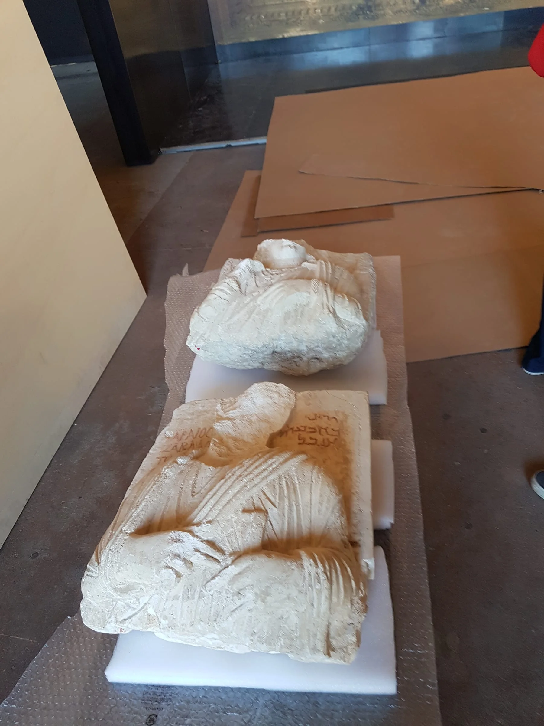 Frammenti di tavolette cuneiformi in argilla appoggiati a un piano di lavoro: scrittura sumerica antica, segni a cuneo, simulazione delle migliaia di tavolette dell'archivio reale