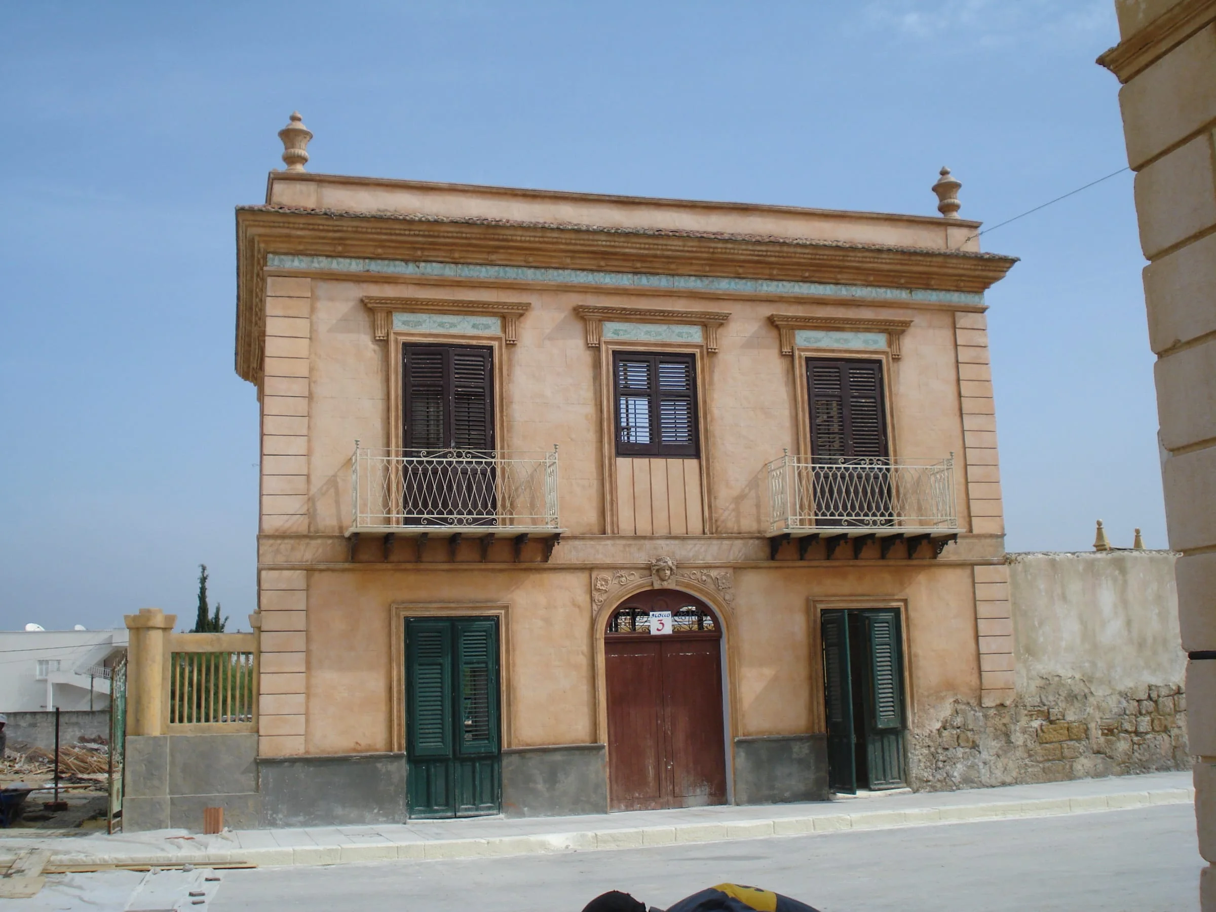 Sicilian Liberty-style palazzo in salmon pink, green shutters, wrought-iron railings: the bourgeois Bagheria of the twentieth century