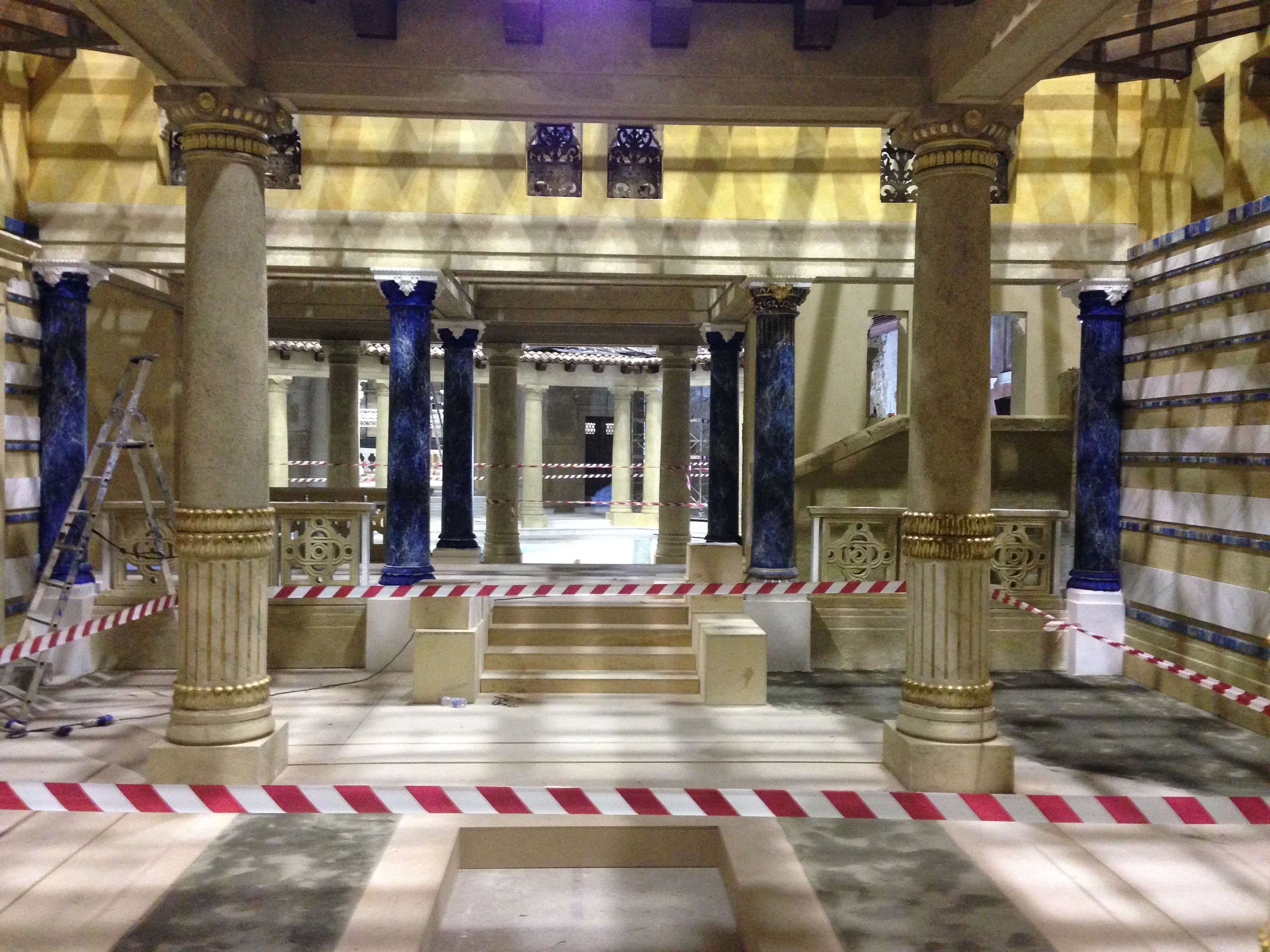 Set del Tempio di Gerusalemme in lavorazione: colonne in finta pietra dorata, fregi in lapislazzuli blu, capitelli classici, pavimentazione a fasce bianche e blu. Cantiere a Cinecittà con nastri rosso-bianchi di delimitazione e impalcature