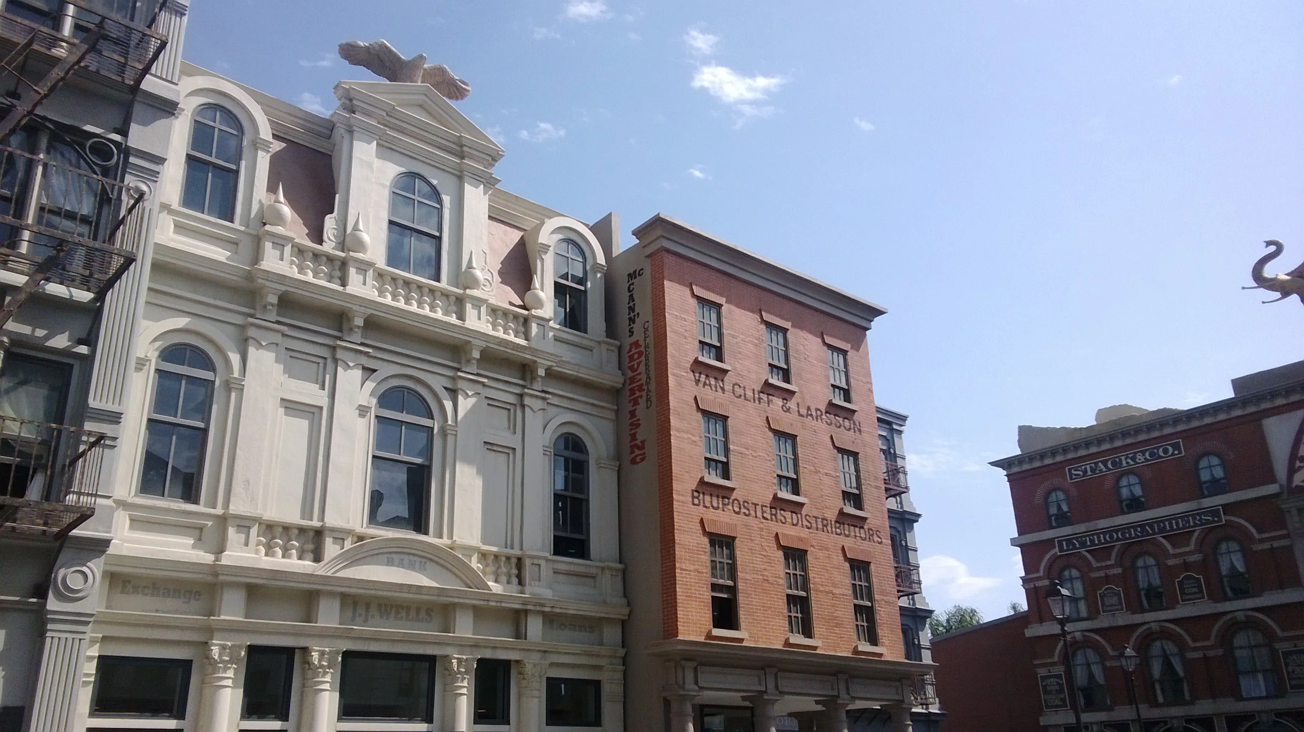 Cinecittà Street, 26 July 2014: white and red-brick Victorian façades, building with iron fire escape, red decorative dragon on the roof, blue sky