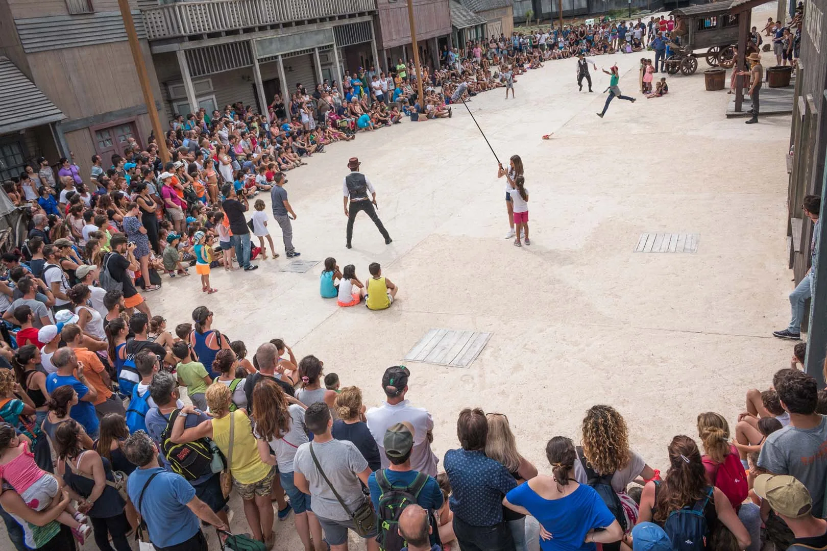 Far West stunt show in the central square of the western village, large audience all around
