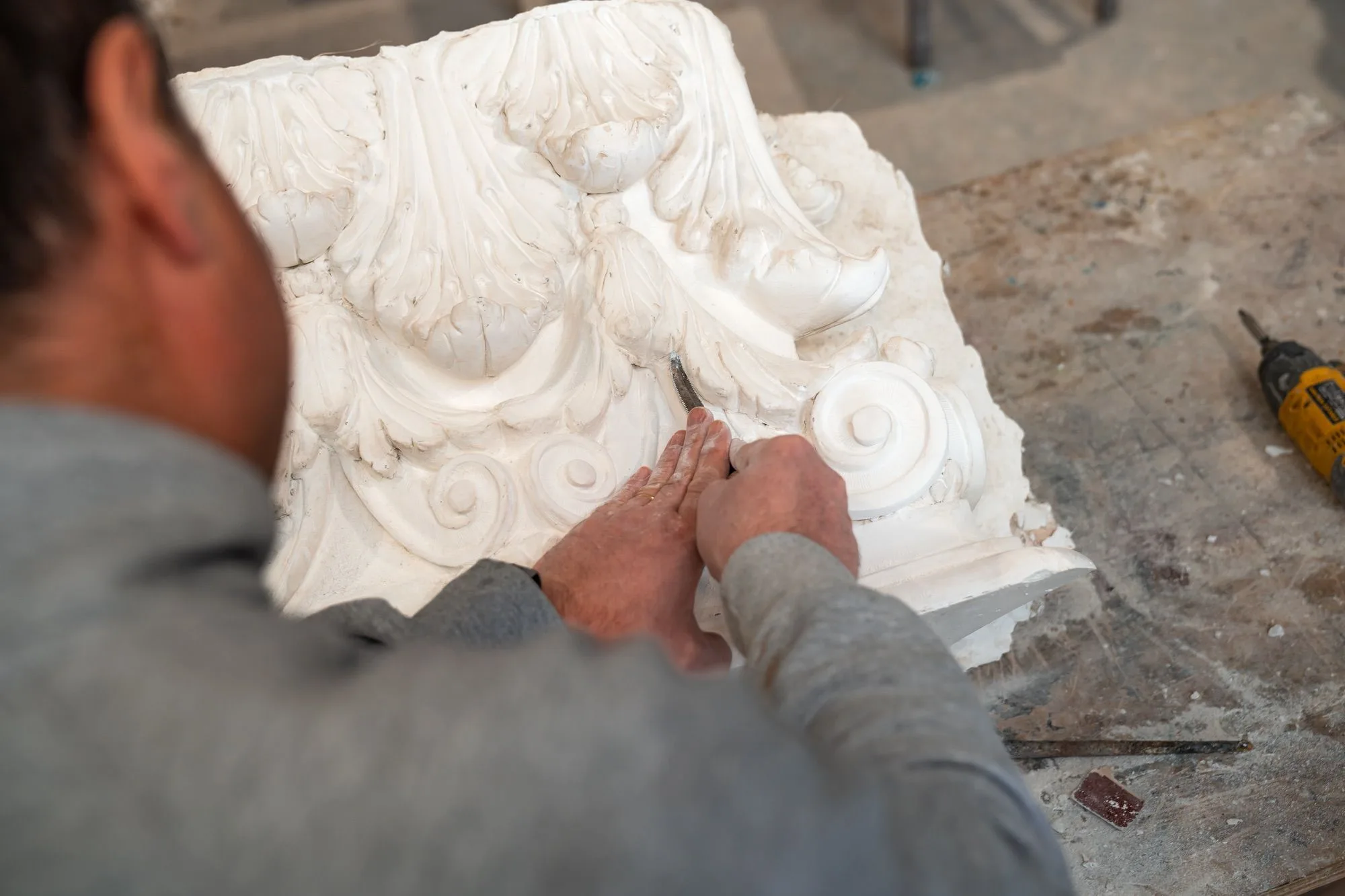 Un nostro dipendente rifinisce a mano un capitello corinzio in vetroresina, con stecca e attrezzi da scultura