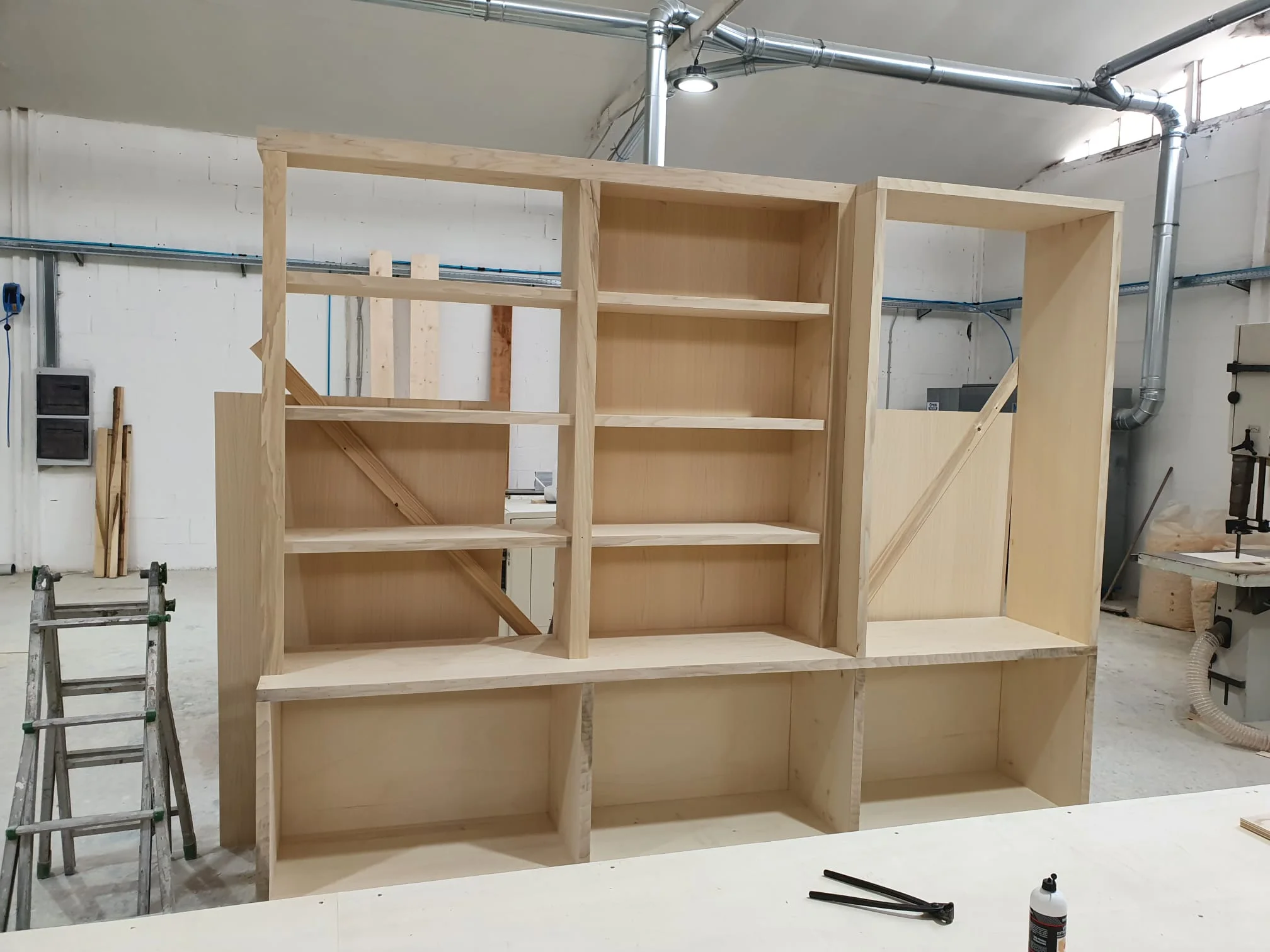 Carpentry workshop view: pieces in progress, sawdust on the floor, electric cutting equipment