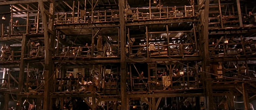 Interno del Brewery: il grande tenement multipiano in legno con ballatoi affollati, lanterne, ponteggi — una delle scenografie più imponenti del film.