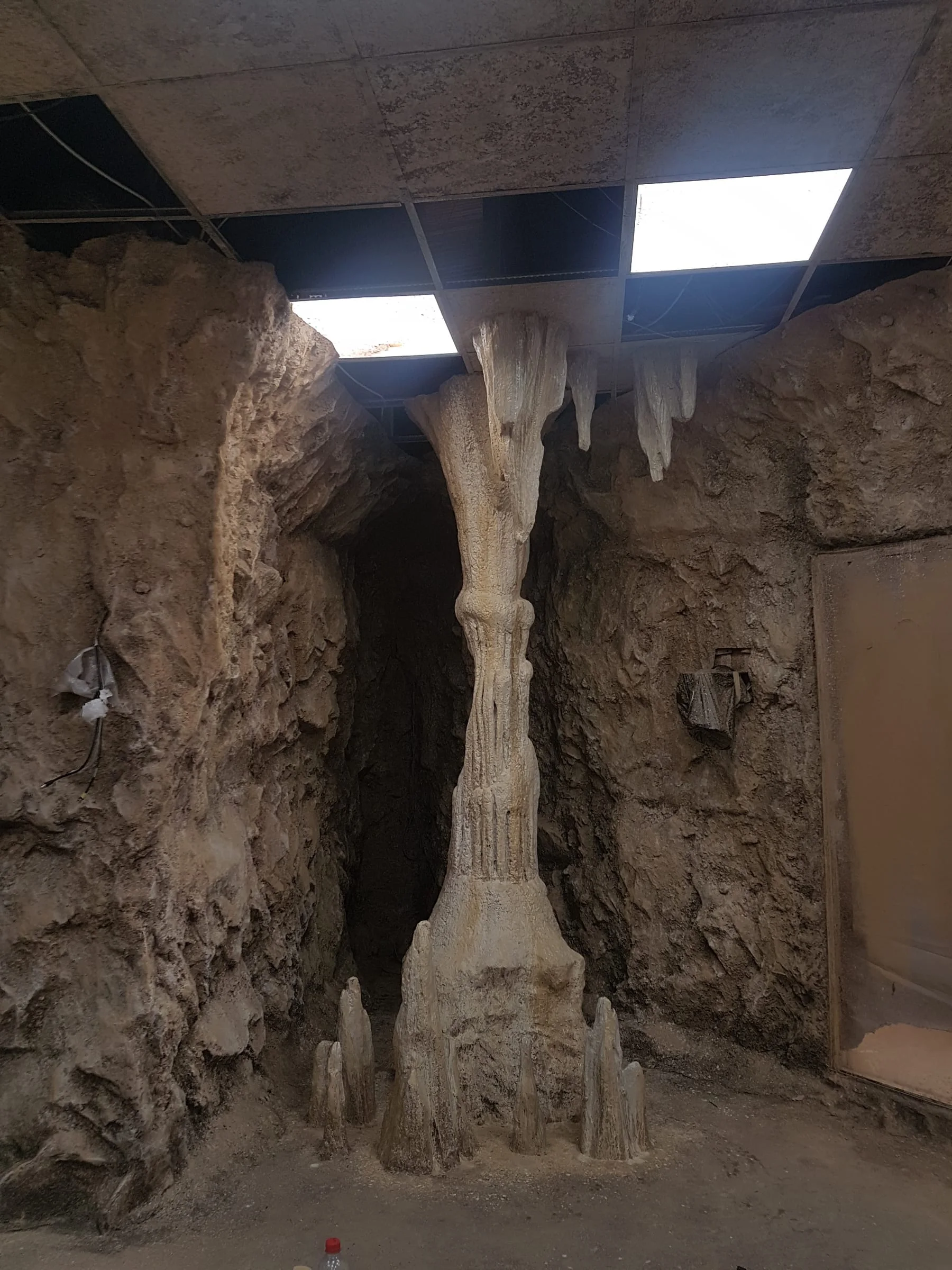 Creation Art workshop, 13 September 2018: sculpted rock walls with short stalactites at the start of the arch, still in the patina phase, two windows with natural light coming in. View of the walls from inside the cave under construction