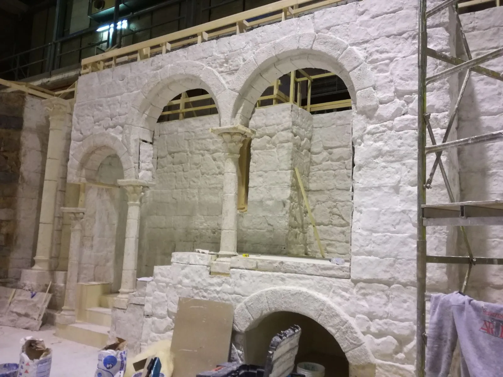 Bifore con colonnine annodate in finta pietra, archi a tutto sesto, mura intonacate a bianco, ponteggio a destra