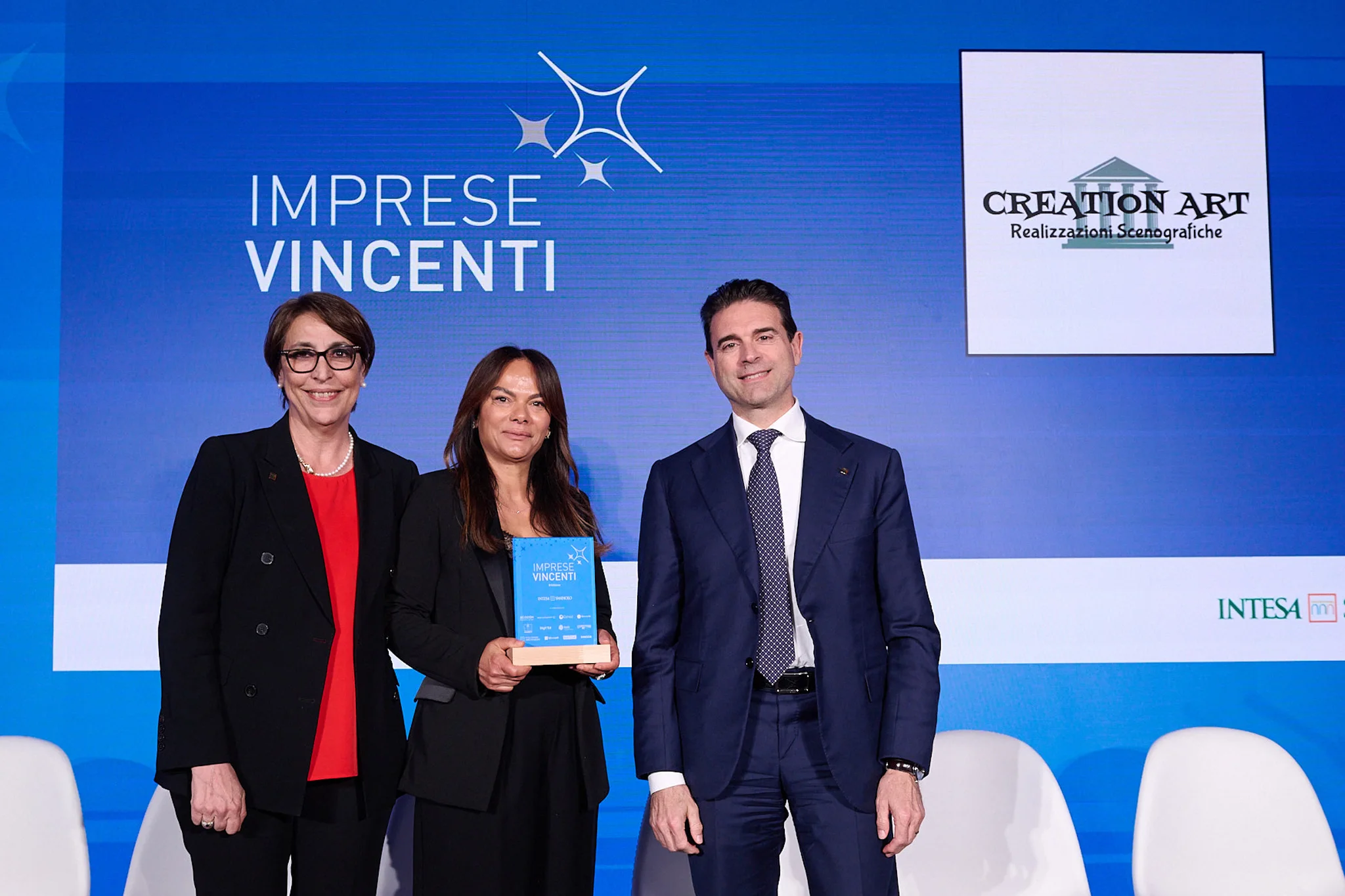 Meriem Rihani riceve il riconoscimento Imprese Vincenti VI edizione per Creation Art, sul palco con i rappresentanti di Intesa Sanpaolo