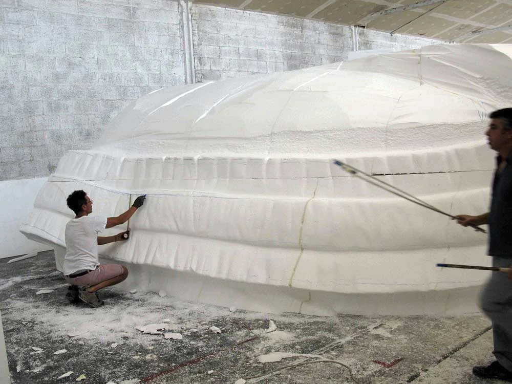 Body section of the elephant sculpted in polystyrene: wide lateral section with skin folds, undulations and veining, front view, raw white material in the workshop