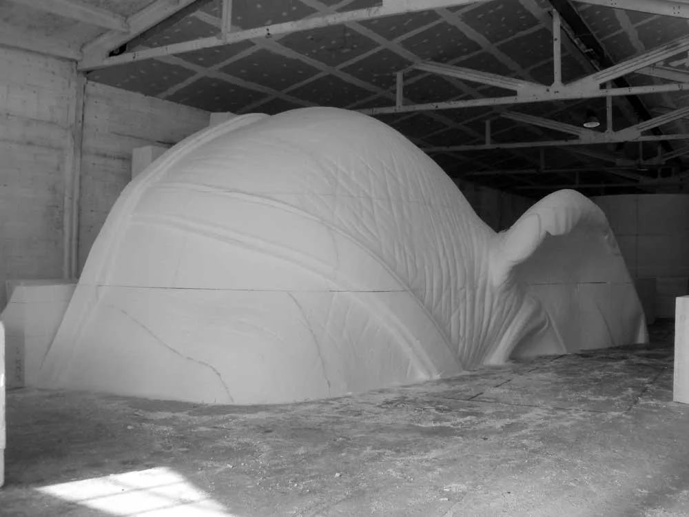 The entire head of the Indiana Adventure elephant sculpted in raw white polystyrene: forehead dome, skin folds, three-quarter view in the workshop warehouse