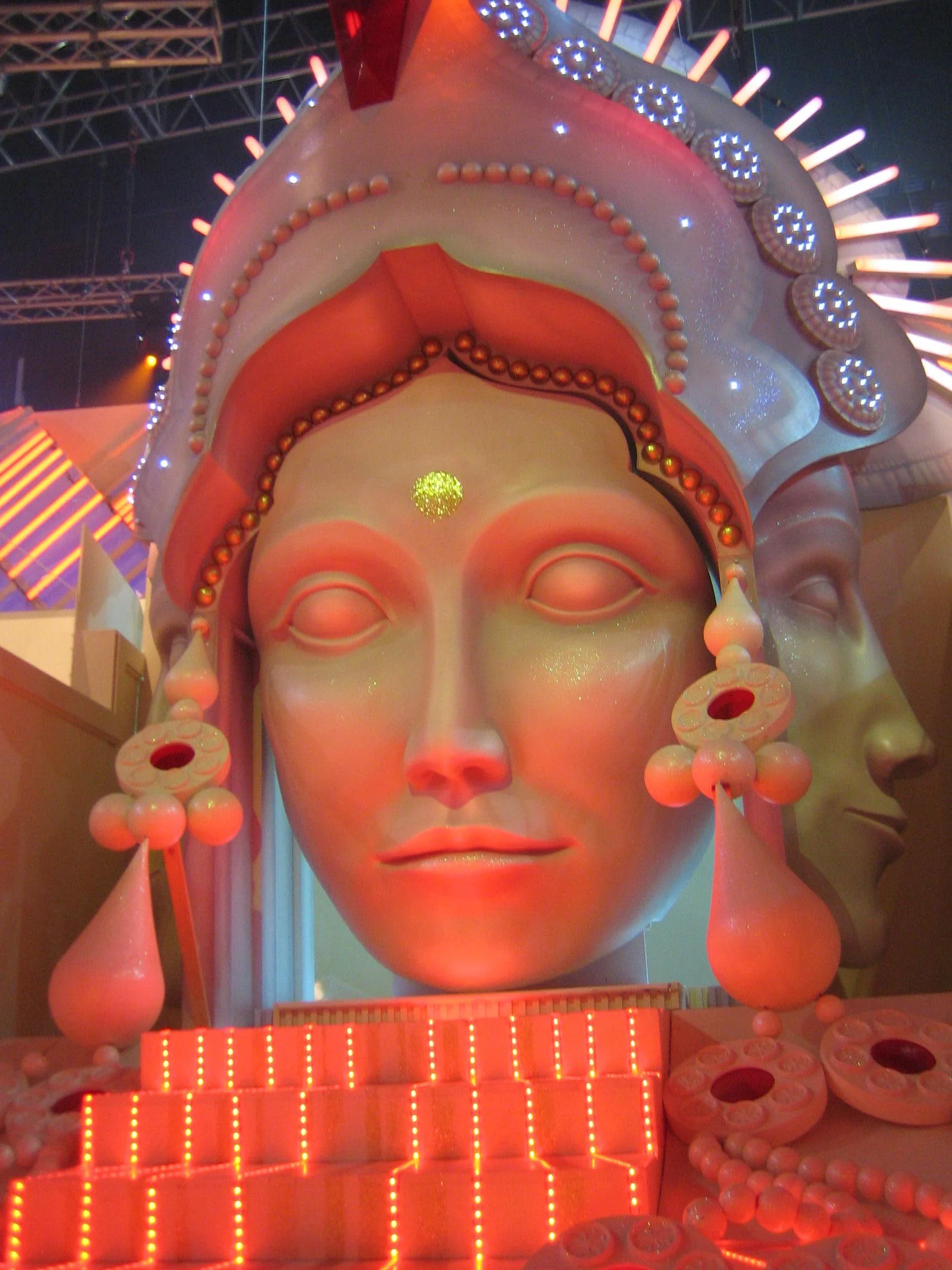 Installation of pink-red LED panels arranged as steps for the studio scenography of the docu-reality La Tribù: Missione India: a female figure in the foreground, in the background the luminous backdrop with horizontal rows of coloured lights
