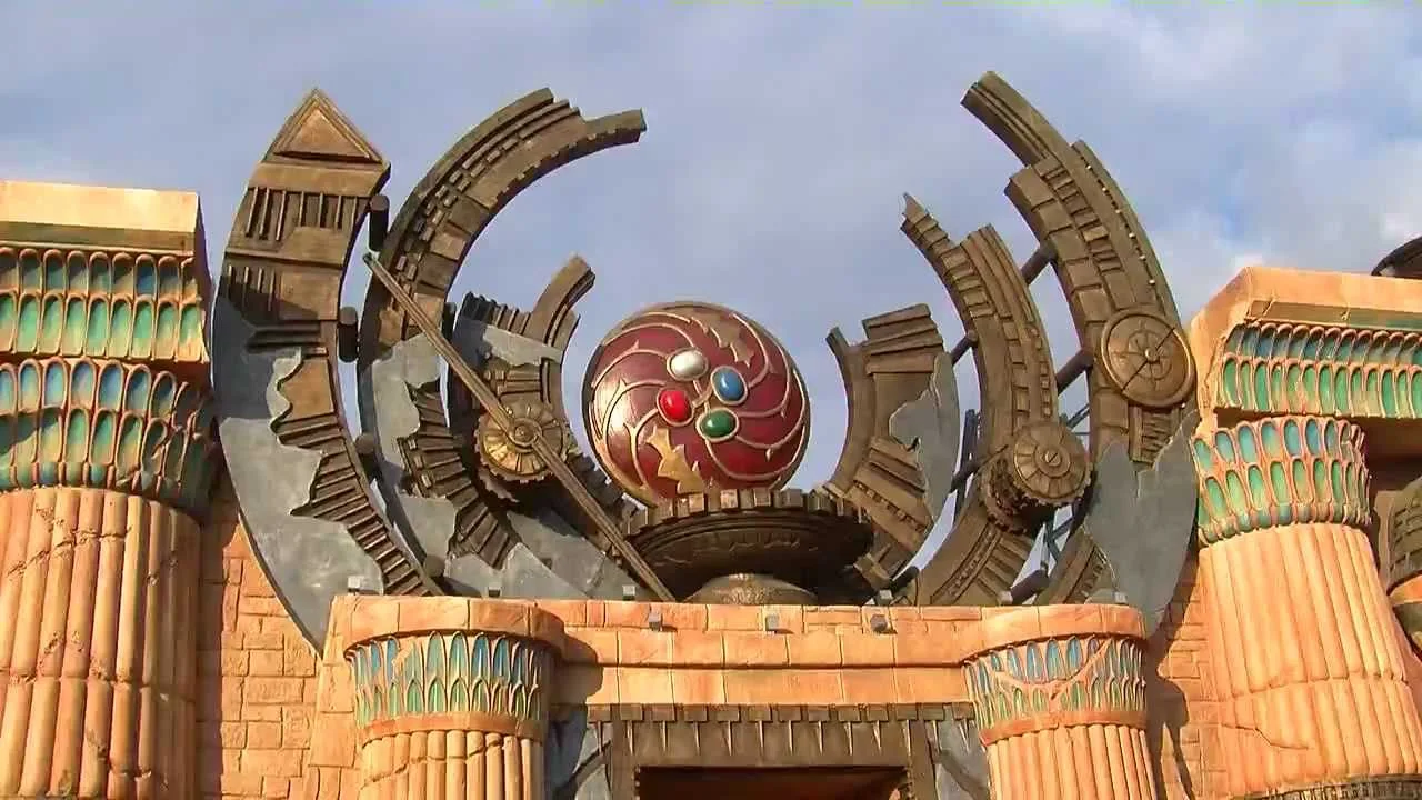 L'attrazione Huntik 5D installata al parco Rainbow MagicLand di Valmontone: ingresso a tema caverna con simboli dei Seeker e degli amuleti dei Titani, scenografie in vetroresina realizzate da Creation Art, colori vivaci della tematizzazione del 2022 post-restyling