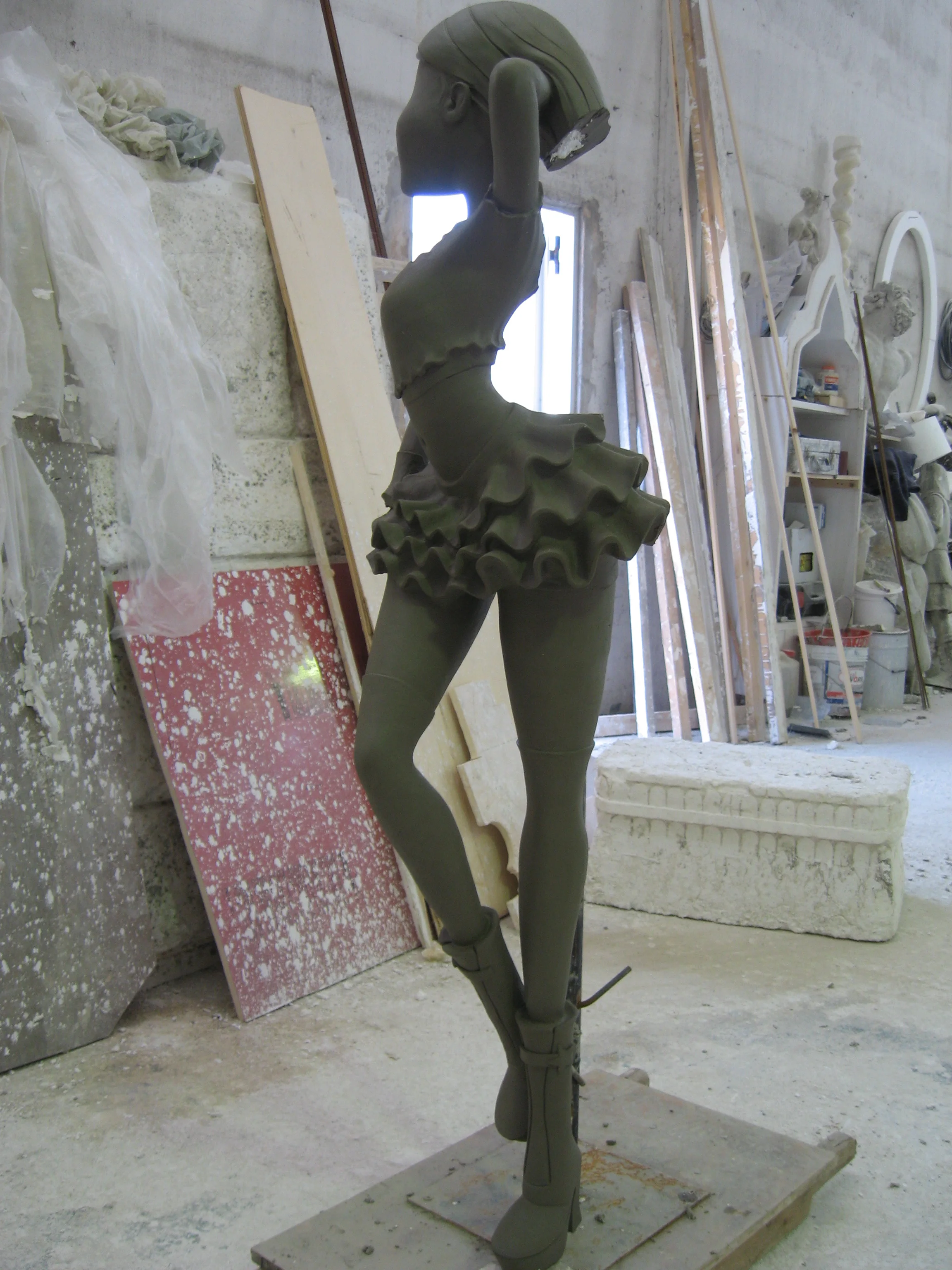 Altra vista del cantiere delle statue Winx nei laboratori Creation Art: scolpitura in corso, materiali e attrezzi sparsi nell'ambiente del laboratorio