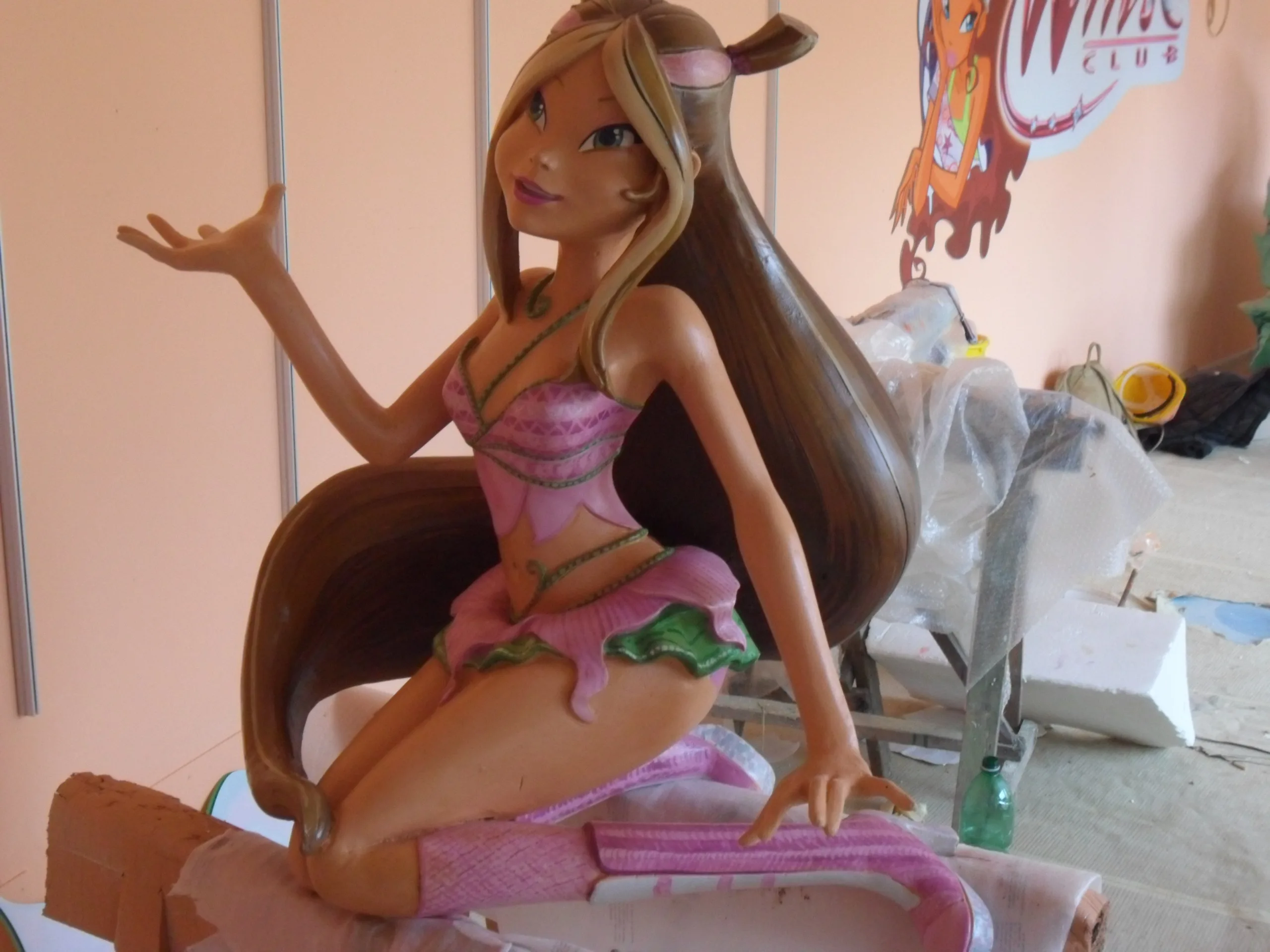 Flora Winx statue sculpted and painted, displayed in front of the Winx Club logo at the Creation Art workshop