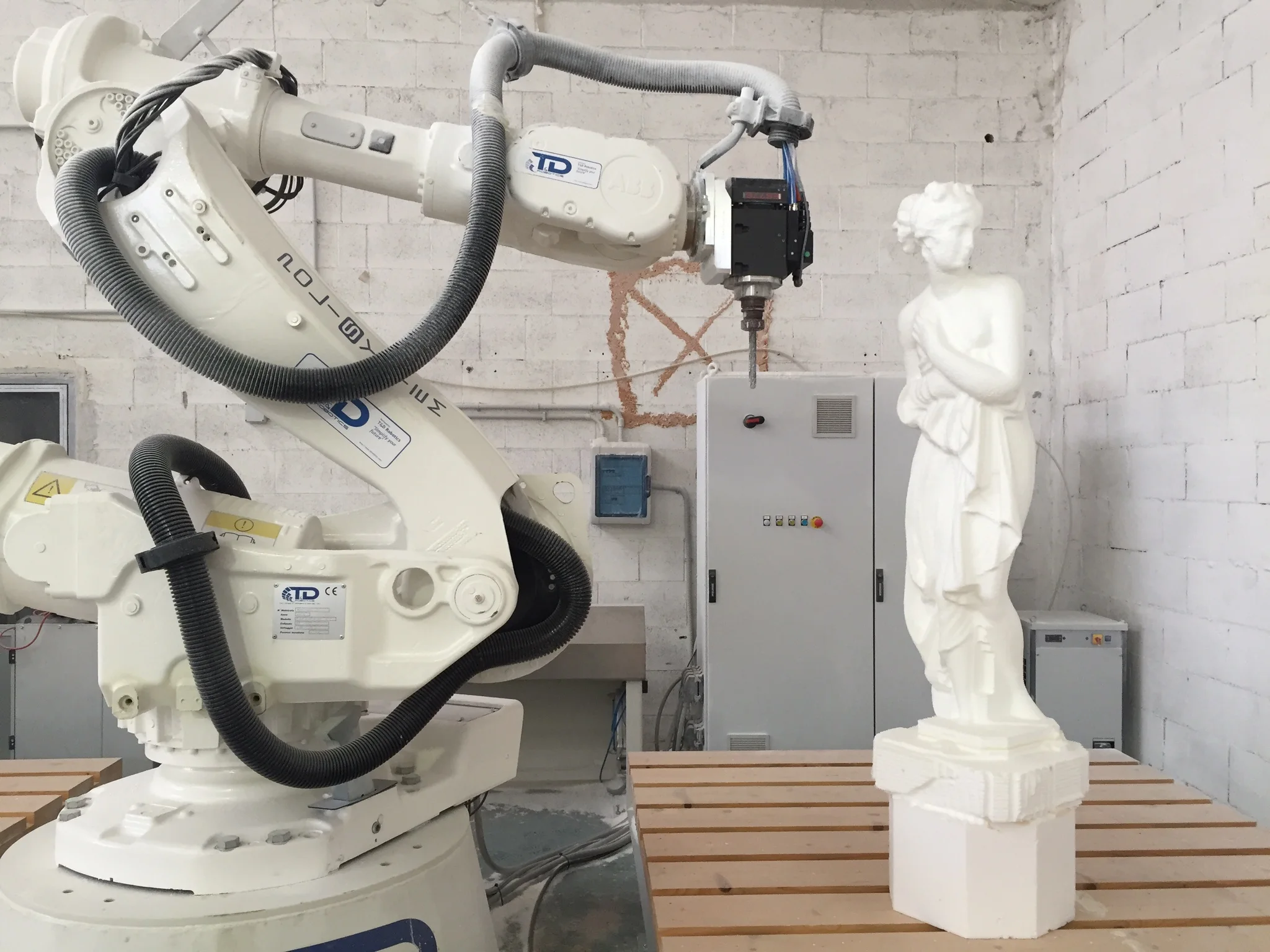 Workshop view with piece in progress under the CNC arm, polystyrene dust on the floor