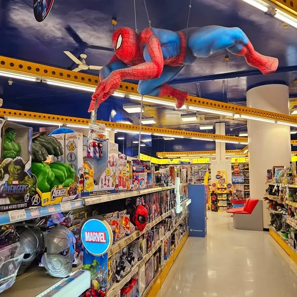 Life-size scenographic Spider-Man sculpted by Creation Art hanging from the ceiling of the Rocco Giocattoli store in Corso Francia, Rome: Marvel red-blue suit, dynamic flying pose with right arm outstretched throwing the web shot, frontal view from the sales floor