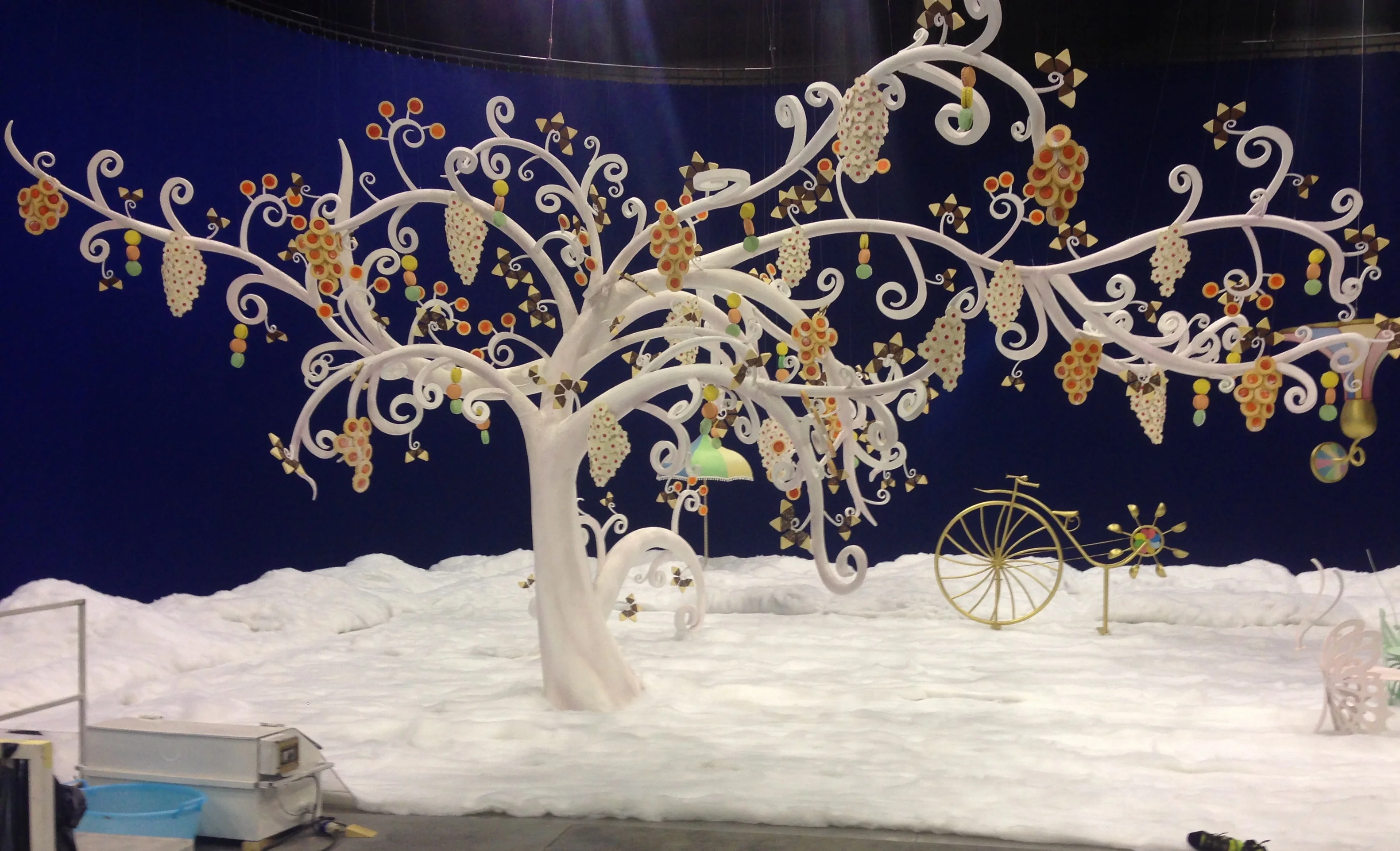 View of the Lavazza set from a different angle: a golden bell at the top, suspended decorations, white scenography with decorative details