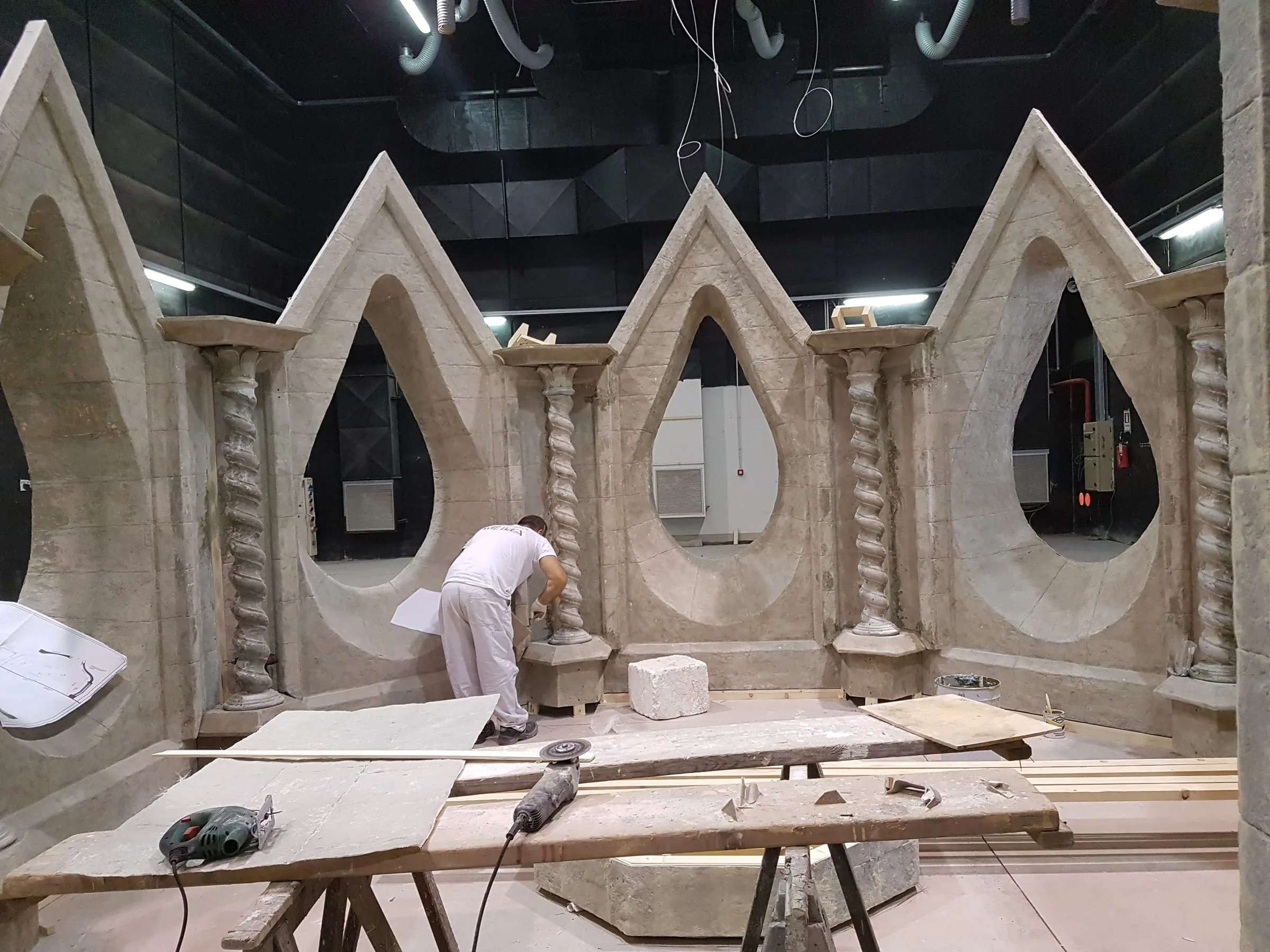 Interior of the refuge under construction: five twisted ogival portals along the wall, sculpted in faux stone, helical columns