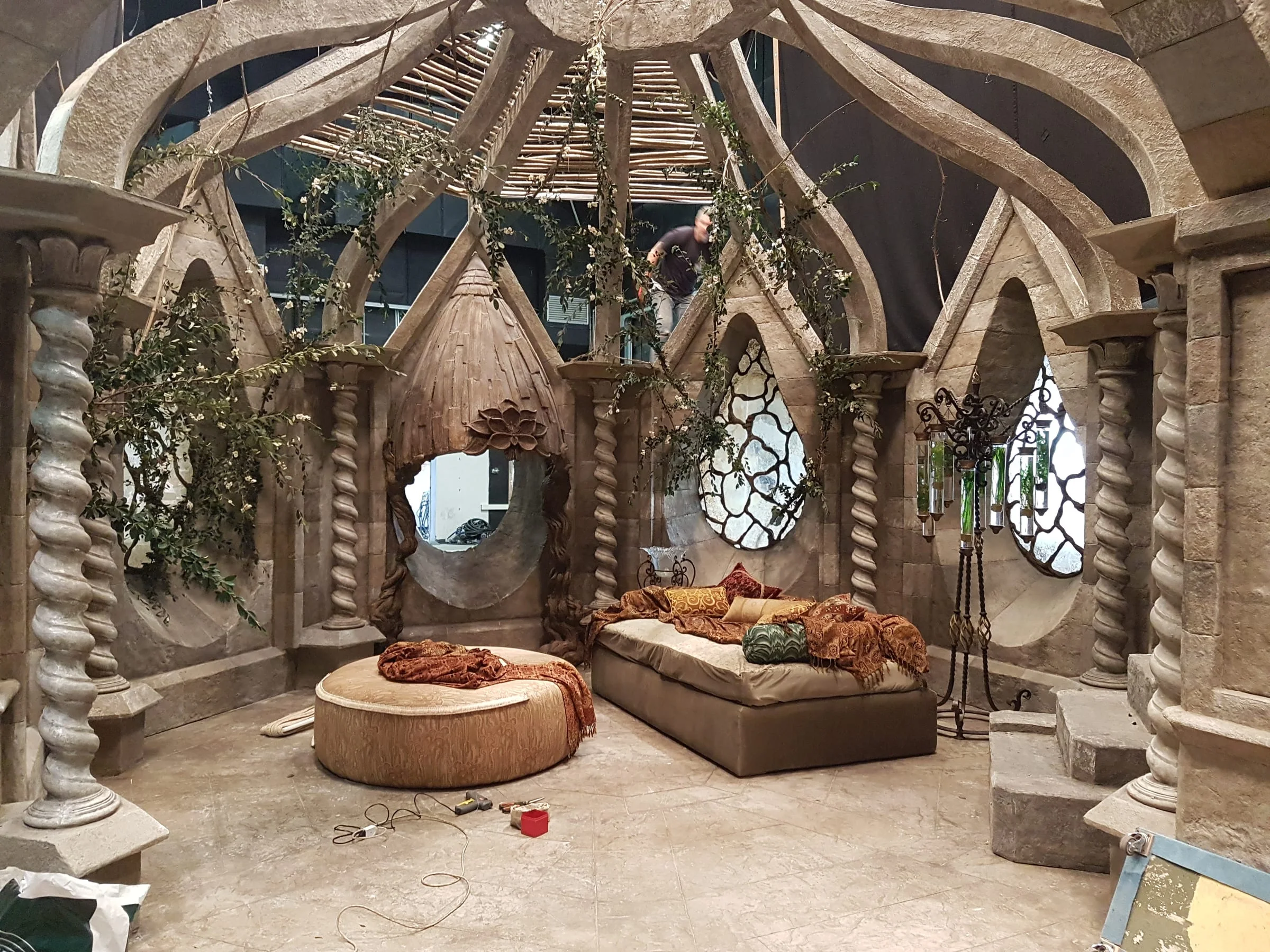 The interior of the refuge built at Cinecittà: an ogival dome of arches in faux stone supported by twisted columns, hanging vegetation, sofa and Oriental cushions on the floor.